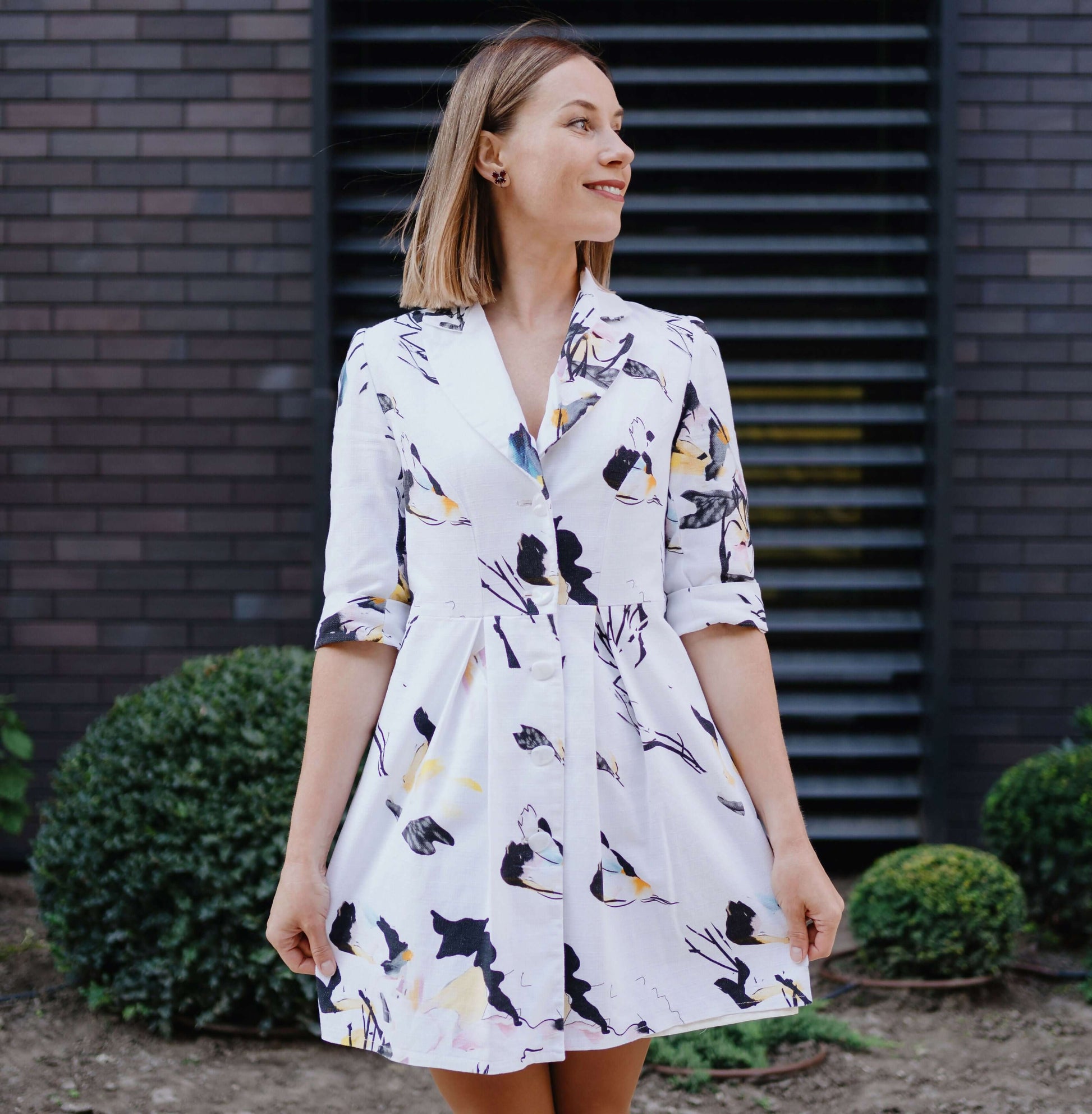 Robe XS-XL - SOULMATE, patron de couture PDF à télécharger, femme portant une robe imprimée florale devant un mur de briques.