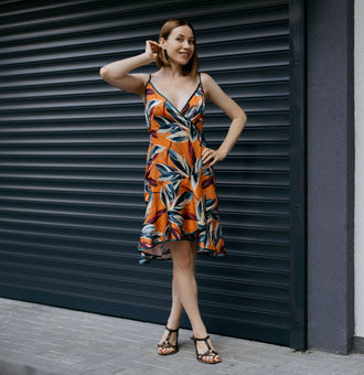 Femme portant une robe d'été colorée devant une porte métallique, mettant en valeur le patron de couture pdf à télécharger de la Robe - XS/L - FALL IN LOVE.