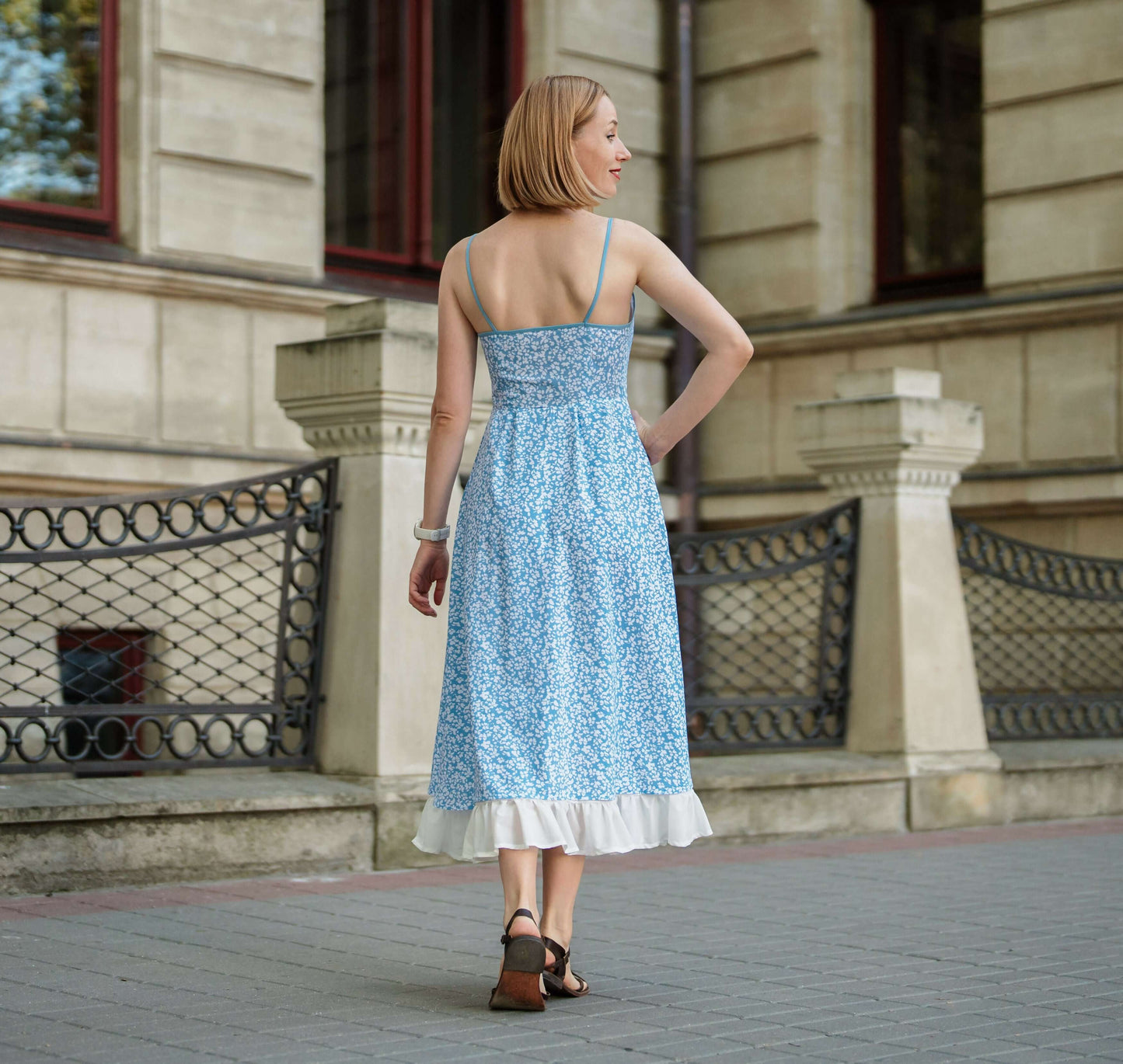 Femme portant une robe d'été devant un bâtiment élégant, mettant en valeur le patron de couture pdf à télécharger, Robe - XS/XL - DELPHINIUM.