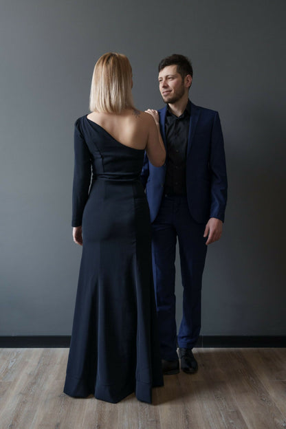 Deux personnes élégantes en tenue de soirée, femme regardant un homme, portant des vêtements formels noirs et bleus.