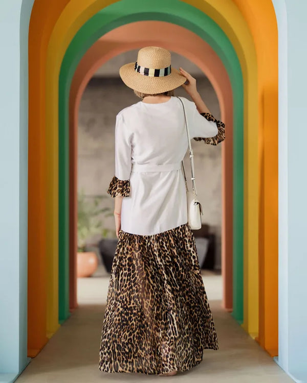 Femme portant une robe élégante avec un chapeau dans un couloir coloré.