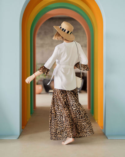 Femme portant une robe motif léopard, debout dans un couloir coloré.