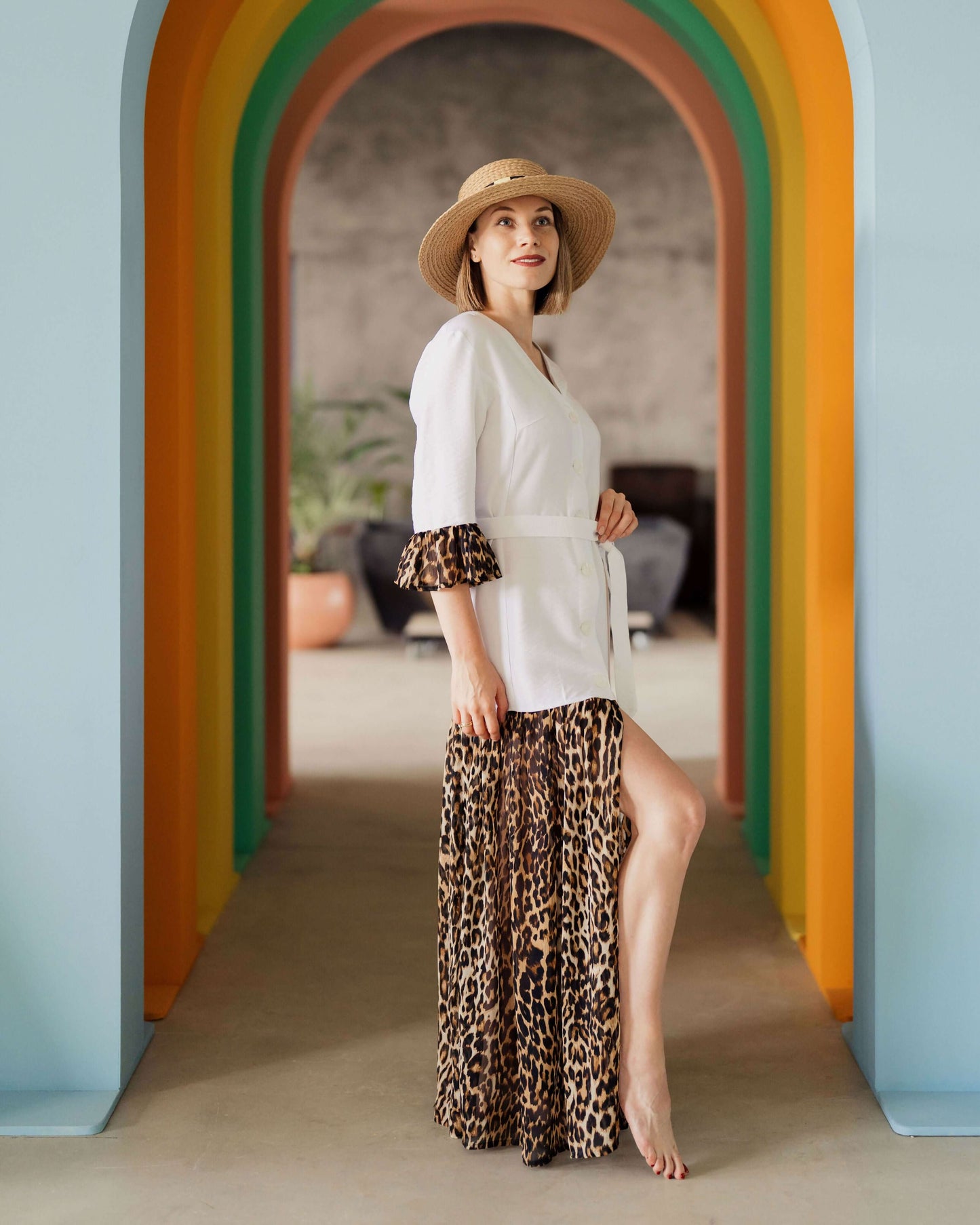 Femme portant une robe "Robe - XXS/XL - BOHEMA" avec un motif léopard, debout sous un arc en ciel coloré. Patron de couture PDF à télécharger.