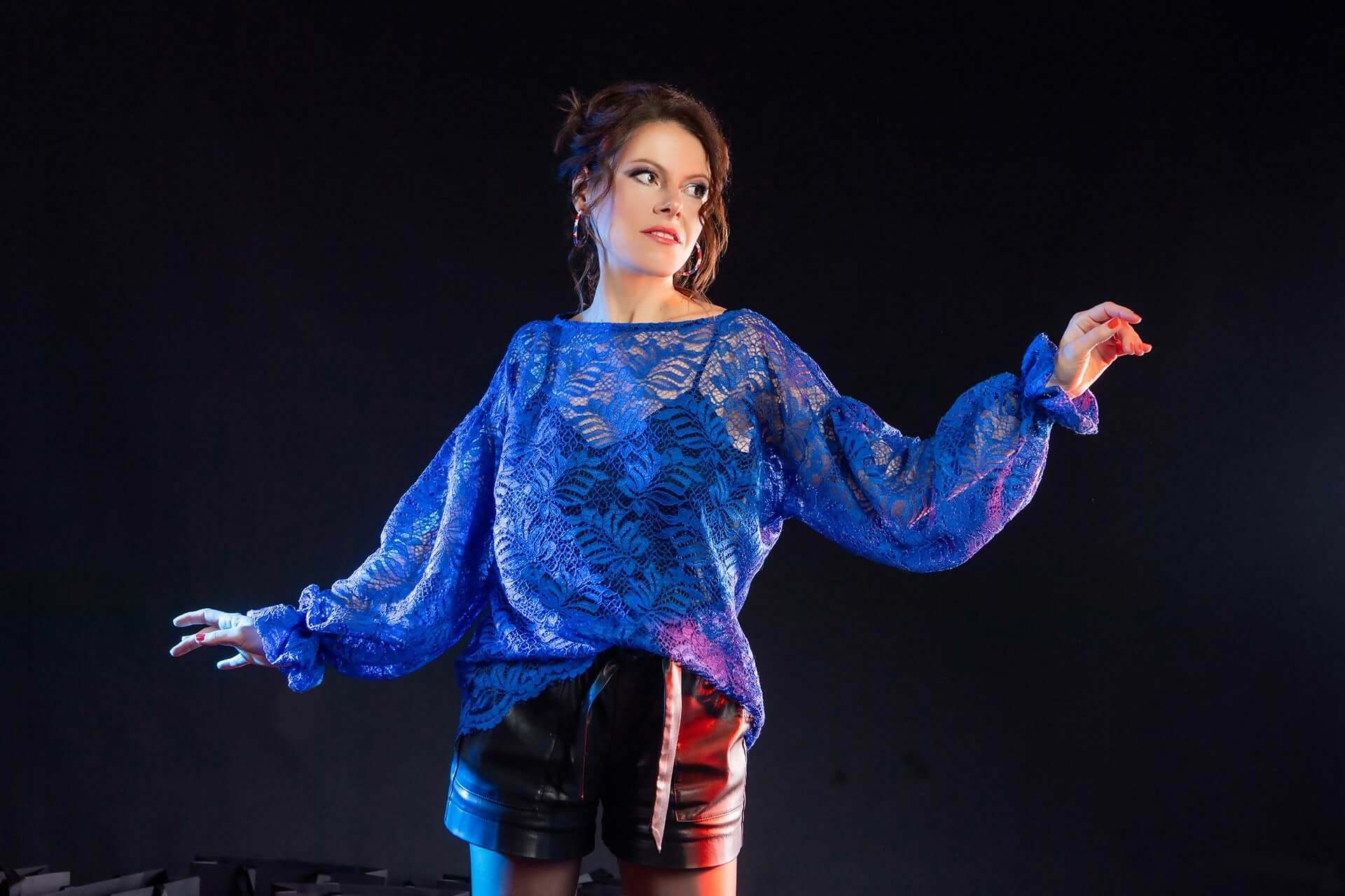 Femme portant le top DAUMESNIL en tissu léger, sur fond sombre, alliant élégance et confort.