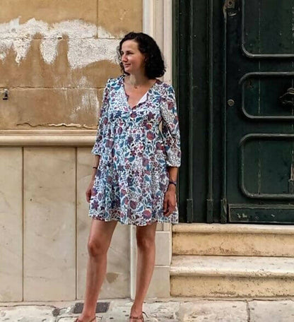 Femme portant une robe légère avec motif, ajustée à la taille, style Sorolla, devant un mur. Patron de couture pdf à télécharger disponible.