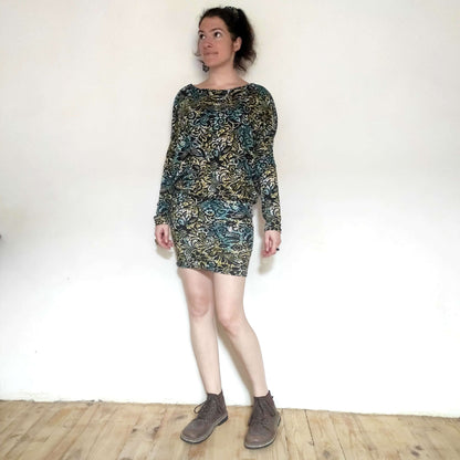 Femme portant la robe/top "Zanka" à encolure bateau, style moderne, tissu en maille élastique, manches longues élégantes.