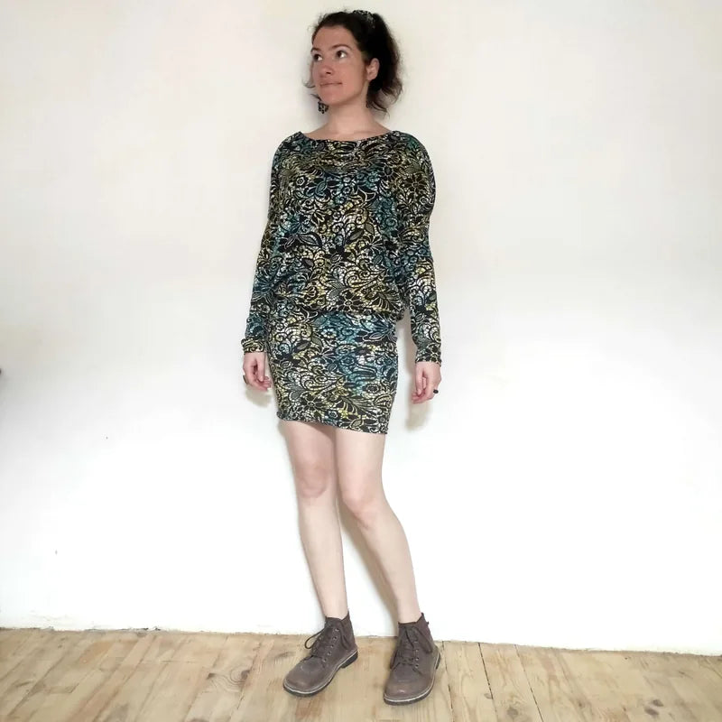 Femme portant la robe/top "Zanka" à encolure bateau, style moderne, tissu en maille élastique, manches longues élégantes.