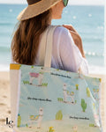 Femme portant le sac cabas Margaret en coton à motif lama cactus, à la plage face à la mer