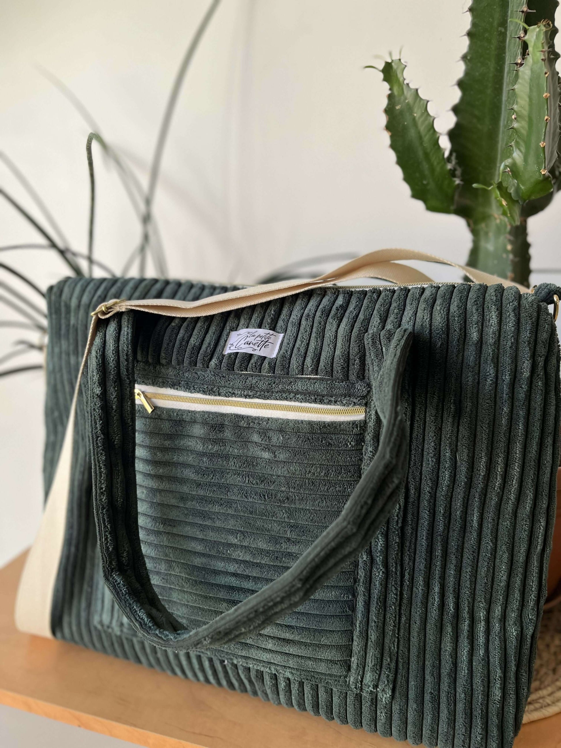 Sacoche d'ordinateur personnalisable faite main avec patron de couture pdf à télécharger, posée sur une table devant un cactus.