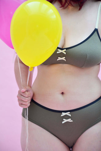 Modèle de bikini chocolat avec lanières, associé à des ballons colorés sur fond rose, stylé et confortable.