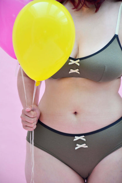 Modèle de bikini chocolat avec lanières, associé à des ballons colorés sur fond rose, stylé et confortable.