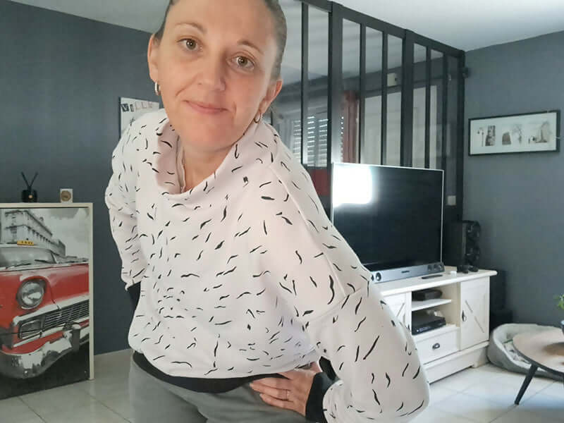 Femme souriante posant dans un salon moderne avec télévision et décoration rétro.