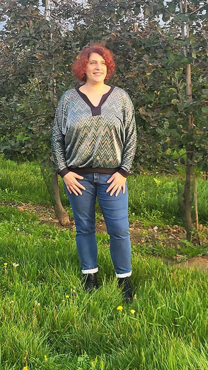 Femme portant un chandail à motifs dans un verger verdoyant.