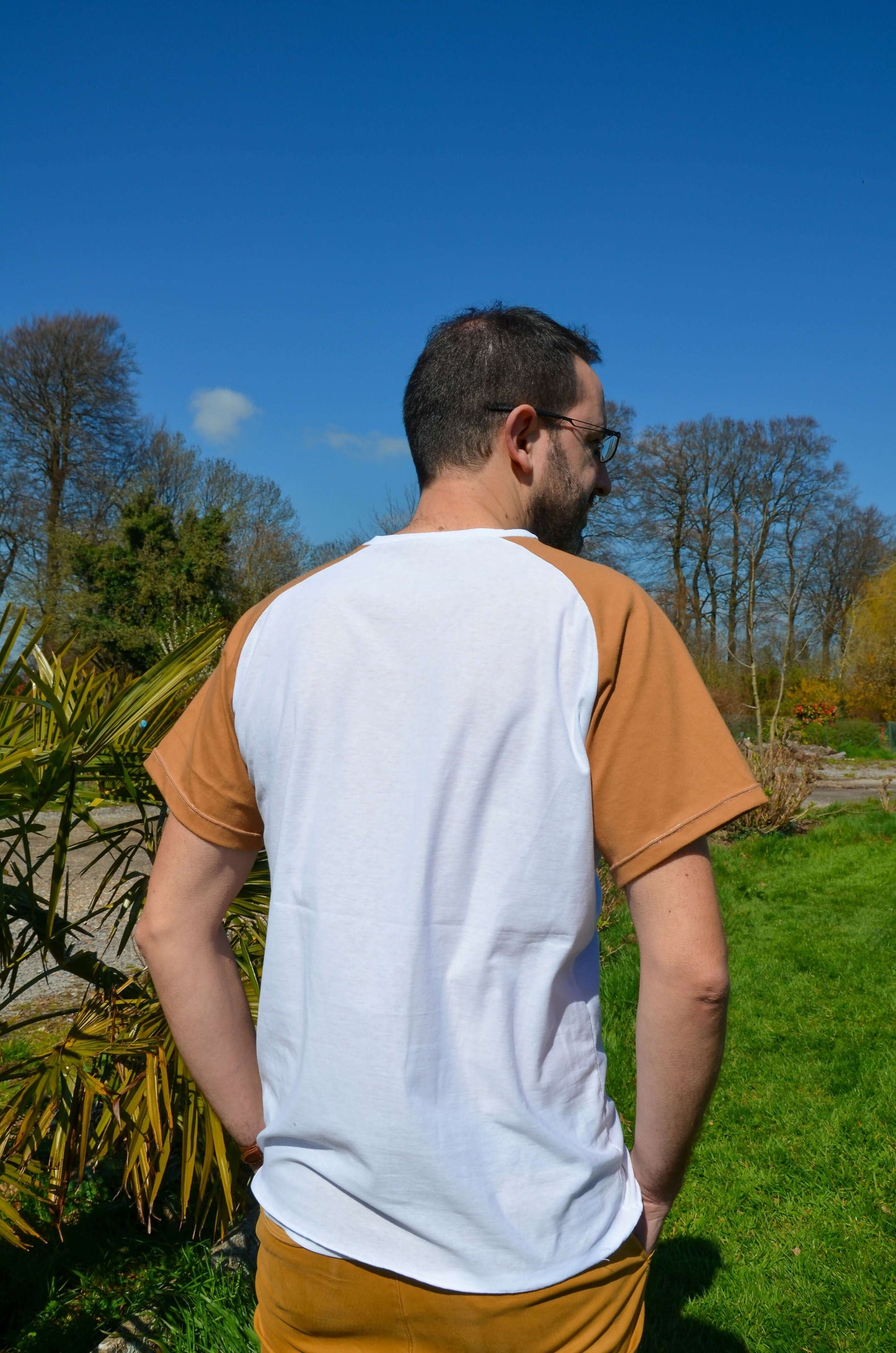 Homme portant un T-shirt à manches raglan beige et blanc, idéal pour créer des styles personnalisés en couture.