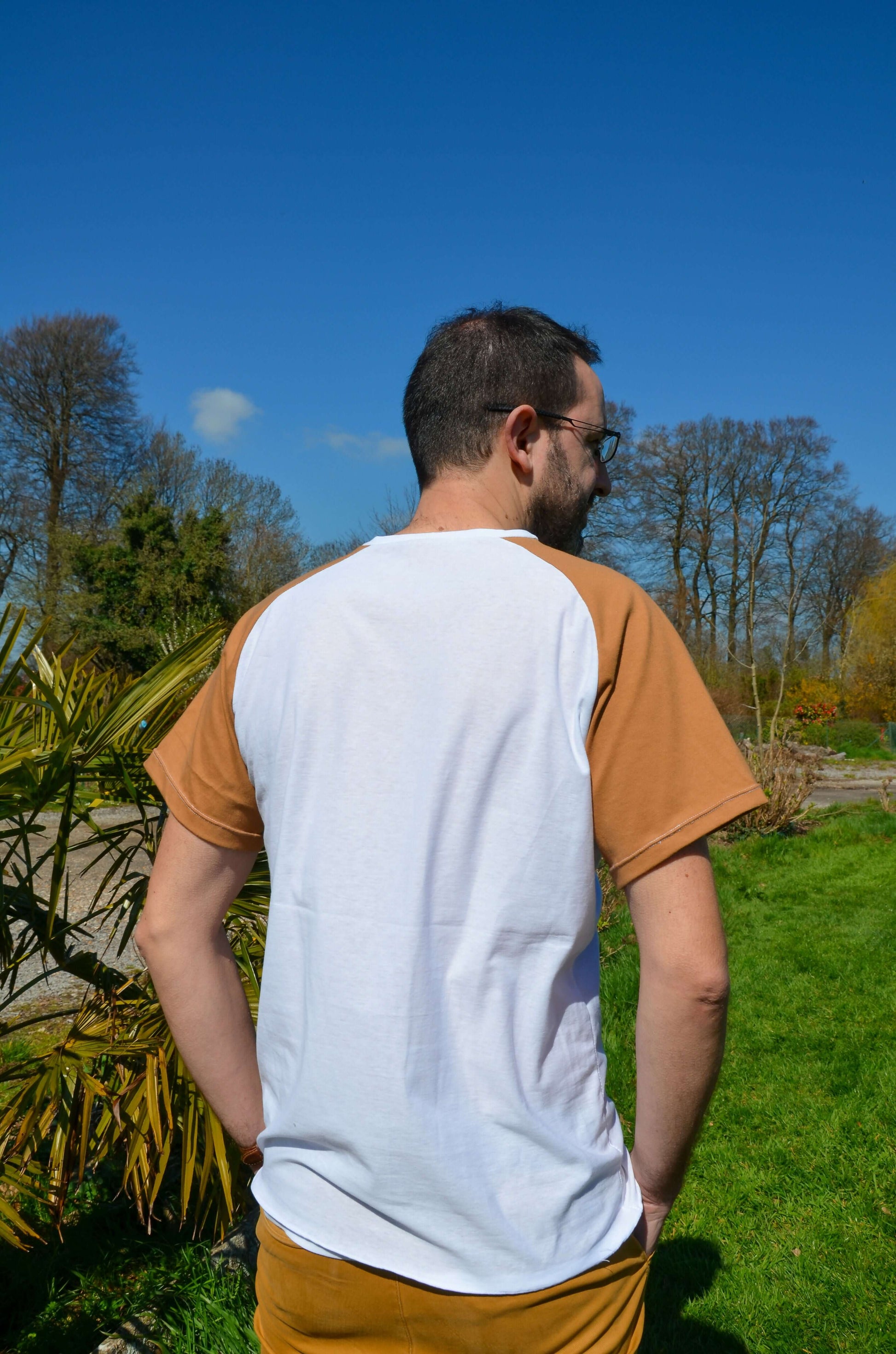 Homme portant un T-shirt à manches raglan beige et blanc, idéal pour créer des styles personnalisés en couture.