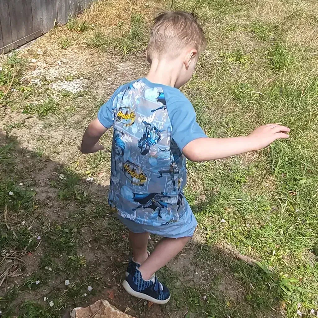 Enfant portant un T-shirt Tao Enfants avec un motif coloré, en train de s'amuser à l'extérieur.