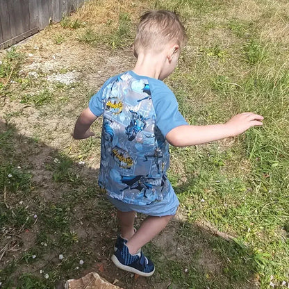Enfant portant un T-shirt Tao Enfants avec un motif coloré, en train de s'amuser à l'extérieur.