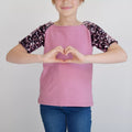 Enfant portant le T-shirt Tao Pack Famille, patron de couture pdf à télécharger, manches à sequins, couleur rose.