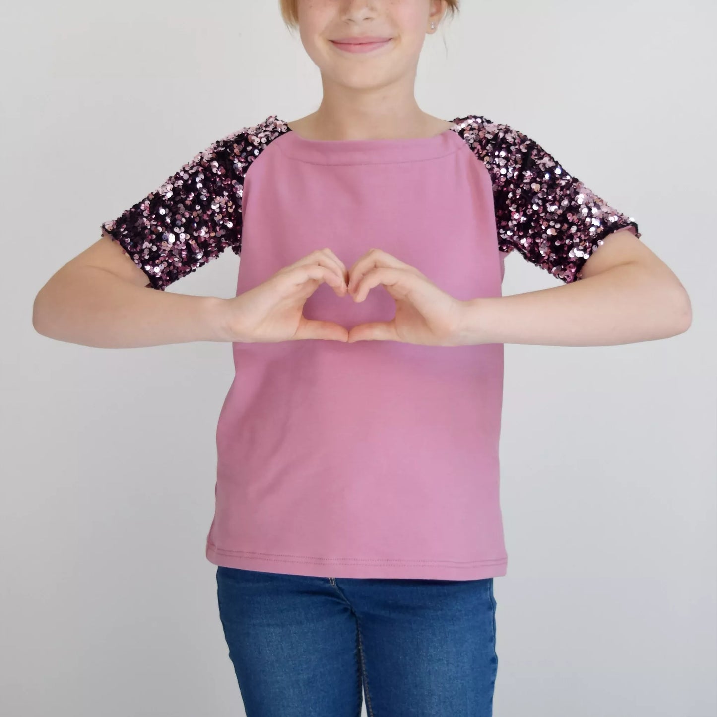 Enfant portant le T-shirt Tao Pack Famille, patron de couture pdf à télécharger, manches à sequins, couleur rose.