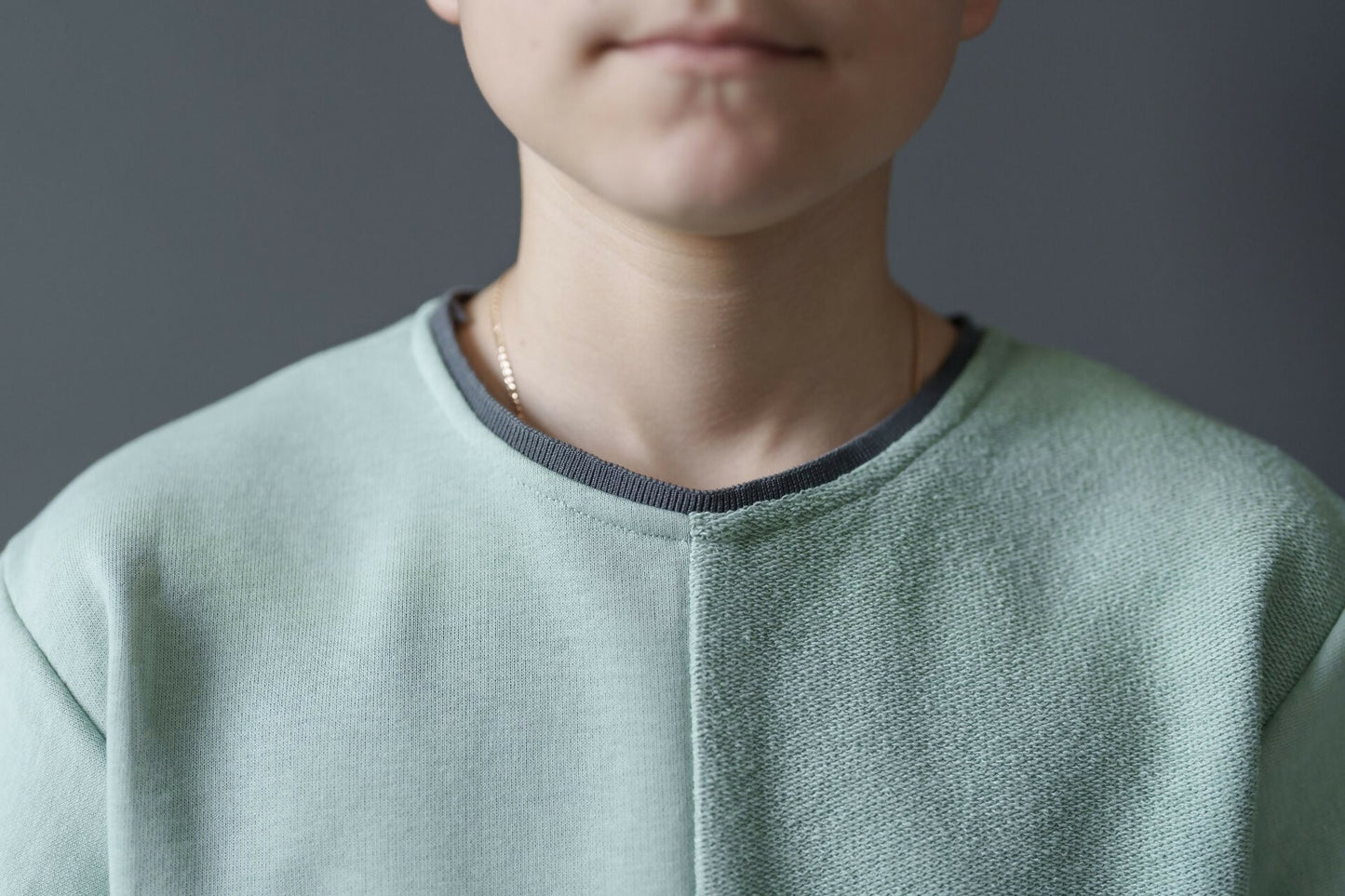 Jeune garçon portant un t-shirt vert clair, vue rapprochée de l'encolure et des épaules.