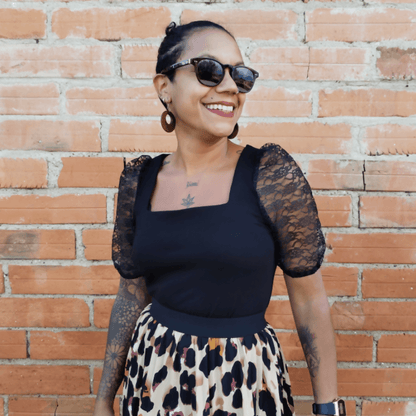 Top Akalat en maille noire avec manches bouffantes, portée avec jupe imprimée, style chic et tendance.