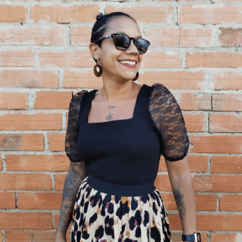 Top Akalat en maille noire avec manches bouffantes, portée avec jupe imprimée, style chic et tendance.