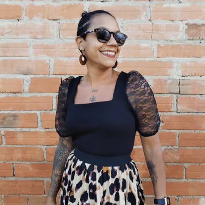 Top Akalat en maille noire avec manches bouffantes, portée avec jupe imprimée, style chic et tendance.