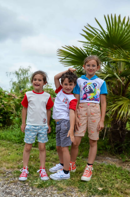Jeunes enfants portant des t-shirts colorés et shorts, souriant au milieu de la nature.