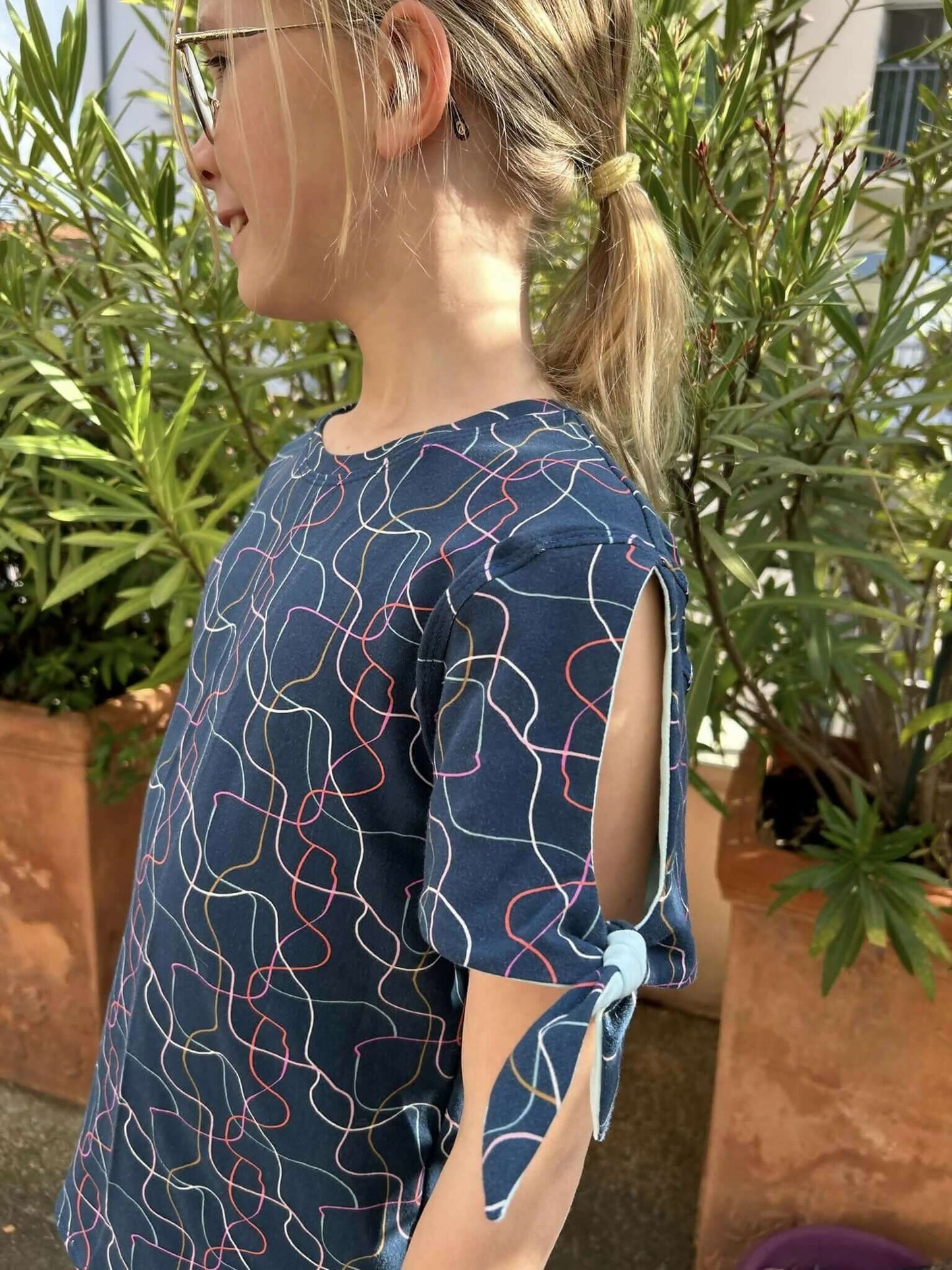 Top Chouchou pattern featuring a girl in a stylish, colorful blouse with tied sleeves outdoors.