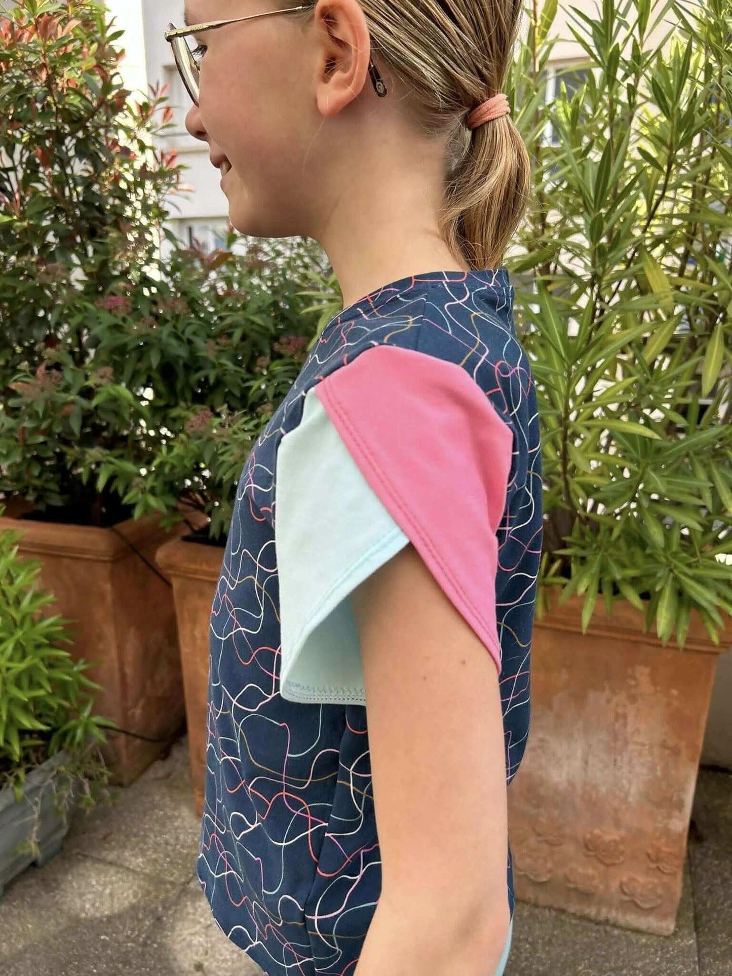 Top Chouchou: enfant portant un t-shirt coloré avec manches courtes, style moderne, apprécié en couture.