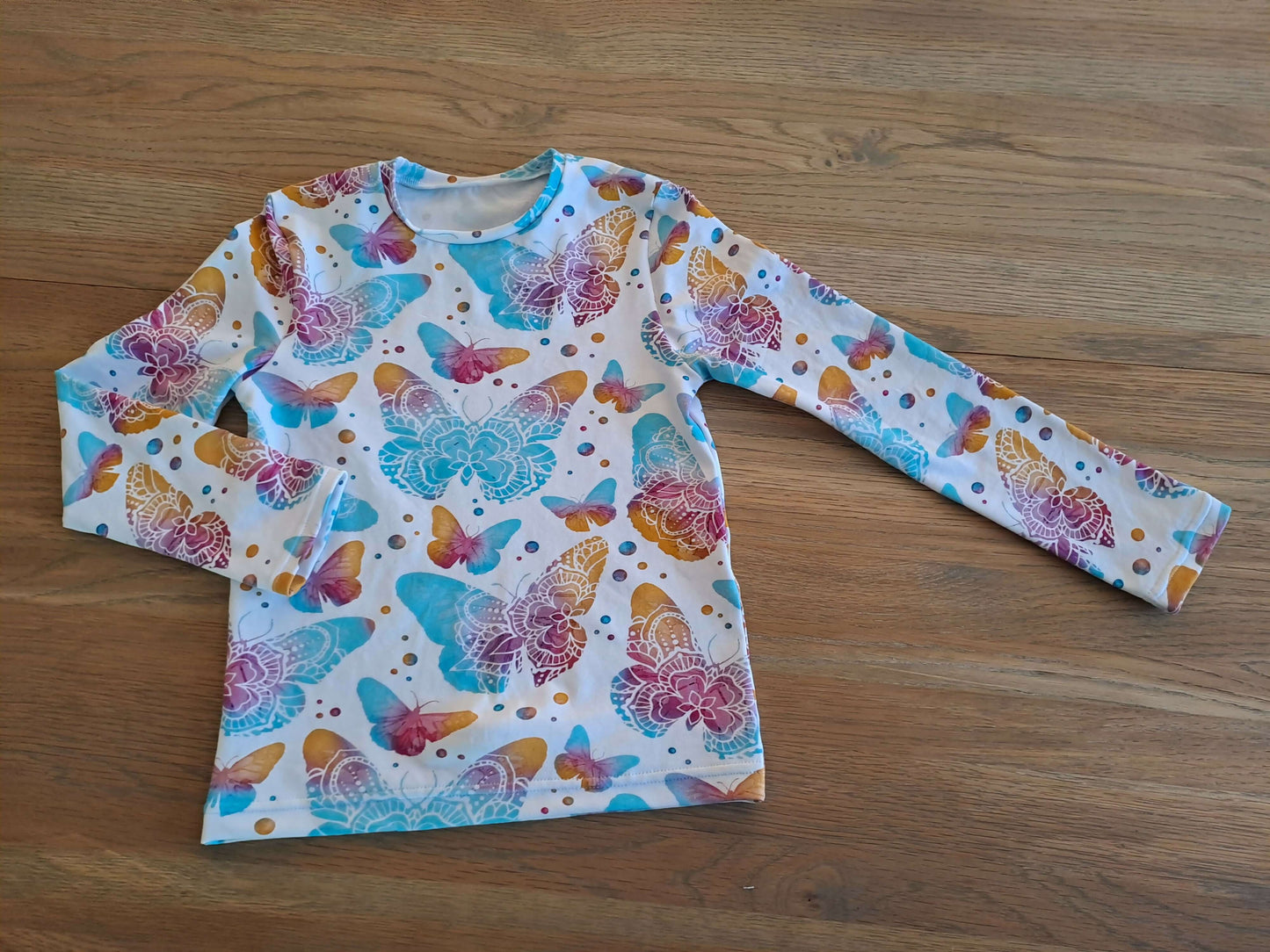 T-shirt à manches longues avec motifs de papillons colorés, idéal pour enfants, style couture créative.