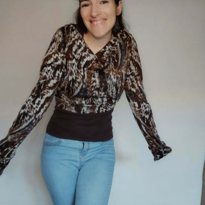 Femme souriante portant un top "Nouipa" à mini col bénitier et manches longues, style moderne et élégant.