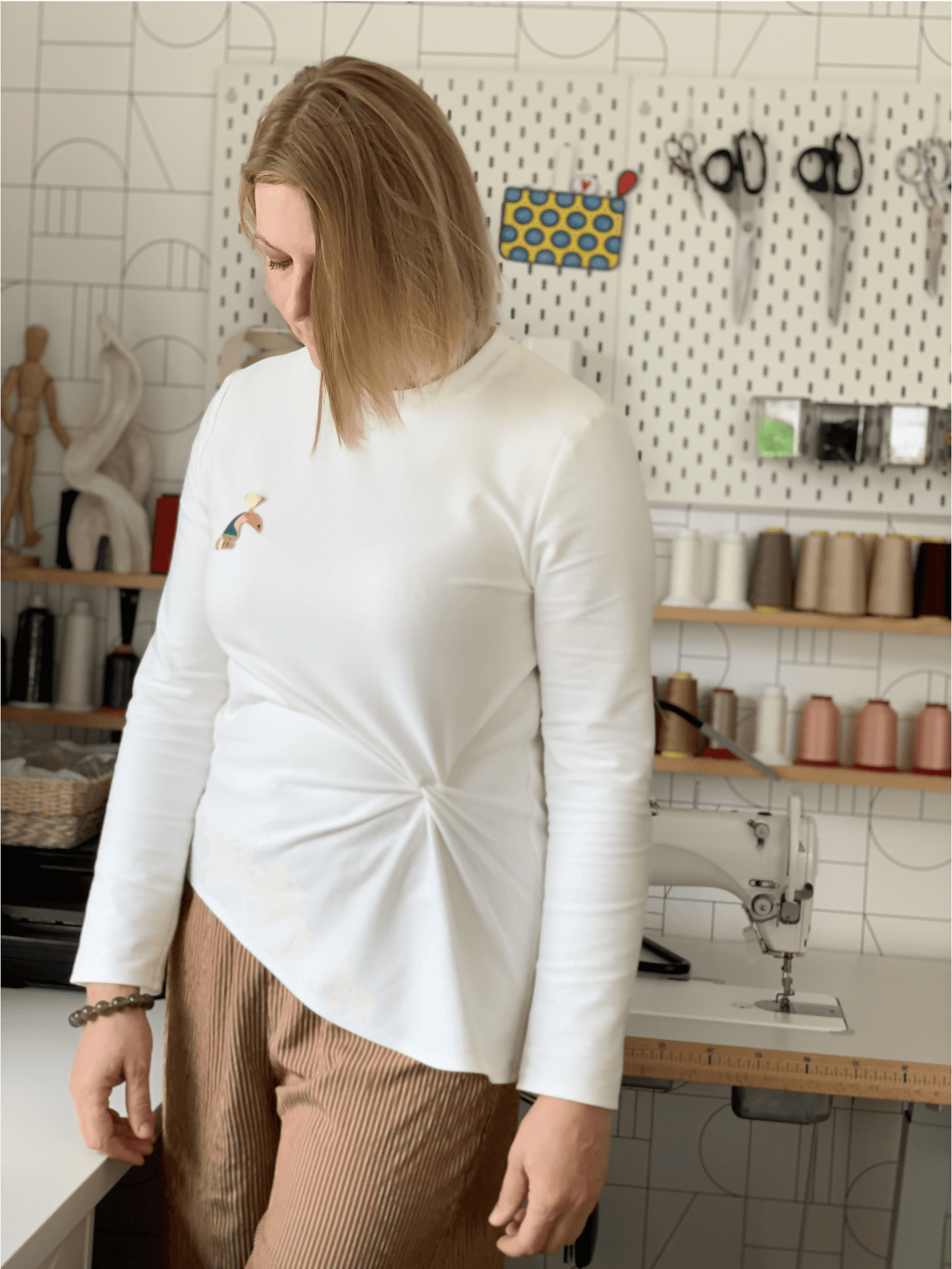 Femme portant le Top Phillip, un patron de couture pdf à télécharger. Haut blanc à manches longues avec noeud devant.