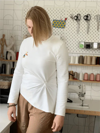 Femme portant le Top Phillip, un patron de couture pdf à télécharger. Haut blanc à manches longues avec noeud devant.