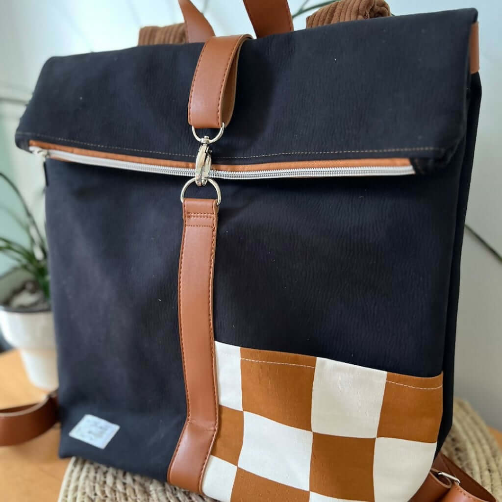 Tutoriel Sac à dos mixte, patron de couture pdf à télécharger, sac noir avec bandes marron et poche à motif, vue de face.