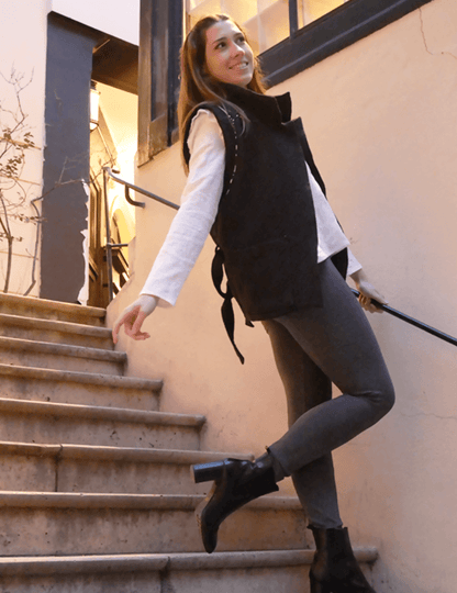 Femme souriante portant une veste Bogota élégante sur des escaliers, alliant confort et style.