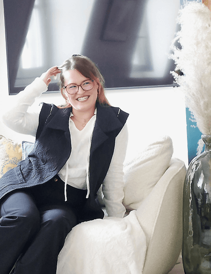 Femme souriante portant la veste Bogota, confortablement assise dans un intérieur élégant, mettant en valeur la couture et le style.