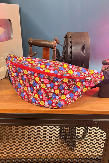 Sac banane Simplo aux motifs fleuris colorés sur une table, devant une décoration vintage.