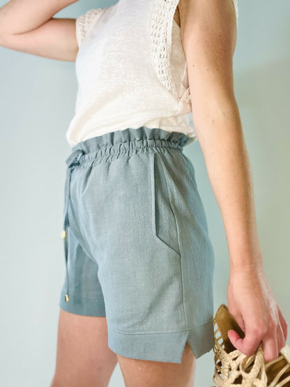 Femme portant un short bleu clair avec taille élastiquée et poches, idéal pour un look dynamique et confortable.