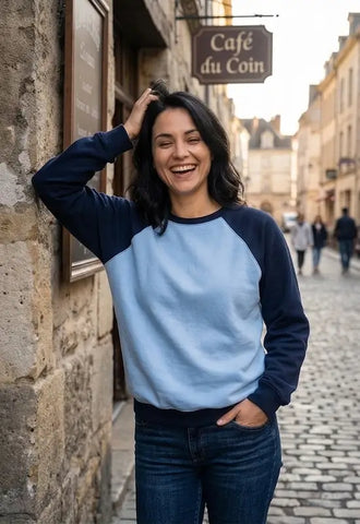Femme souriante portant le Sweat Livarot Adulte Taille 34 à 54, patron de couture pdf à télécharger, dans une rue française pittoresque.