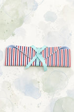 Pochette de toilette en coton rayé rouge, blanc et bleu, fermée par un ruban turquoise — patron de couture PDF gratuit