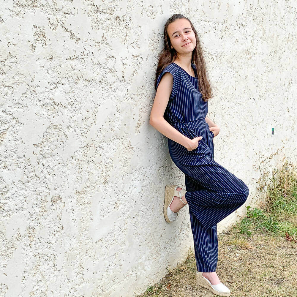 Femme portant la Combinaison, pantalon, 34 au 56, 4 statures – Vanille, patron de couture pdf à télécharger, adossée à un mur.