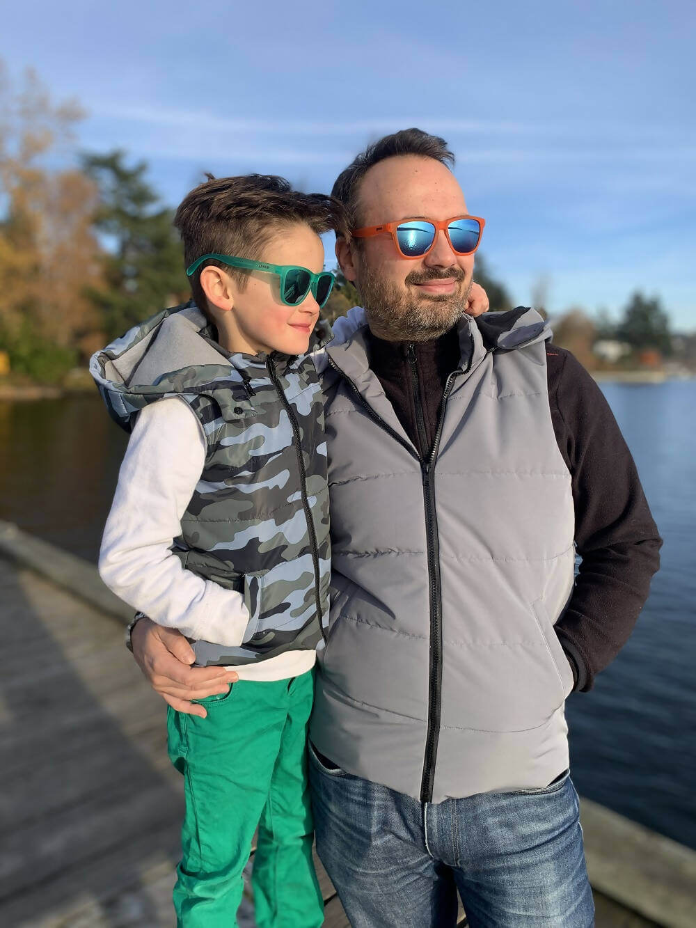 Père et fils portant Duo KEZIA - Doudoune sans manches mixte au bord d'un lac, idéale pour la mi-saison, patron de couture pdf à télécharger.