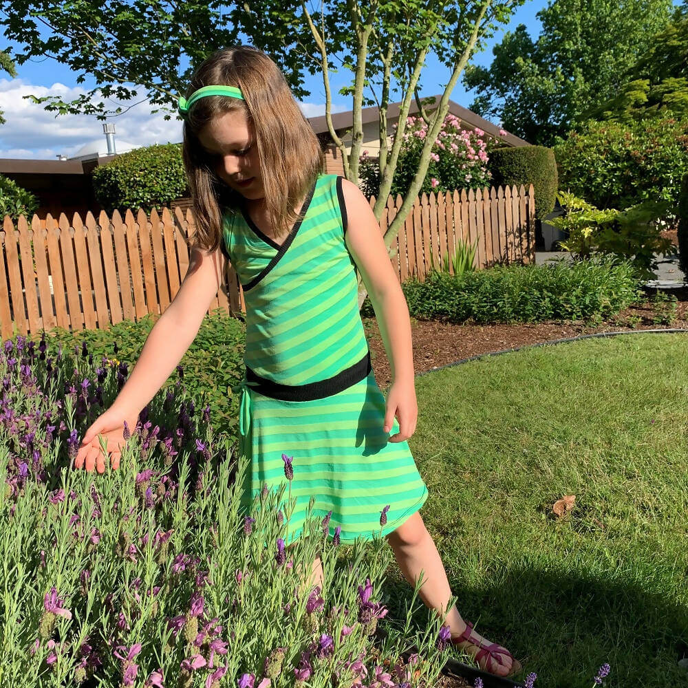 Jeune fille portant la Duo SANDY - Robe cache coeur pour femmes (34 à 54) et filles (2 à 16 Ans) dans un jardin fleuri.