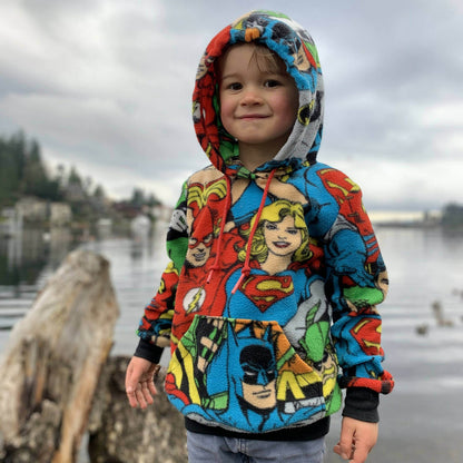 Enfant portant un sweatshirt coloré près d'un lac, idéal pour le refroidissement des jeunes aventures.