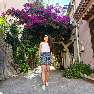 Femme portant la Jupe / Short Bibiche - T34 à 48, entourée de fleurs pour un look estival, patron de couture pdf à télécharger.