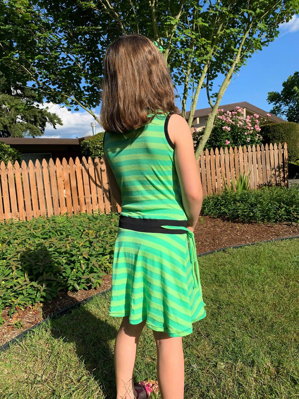 Fille portant la Mini-SANDY - Robe cache-coeur pour filles du 2 au 16 Ans, patron de couture pdf à télécharger, en tissu vert rayé.