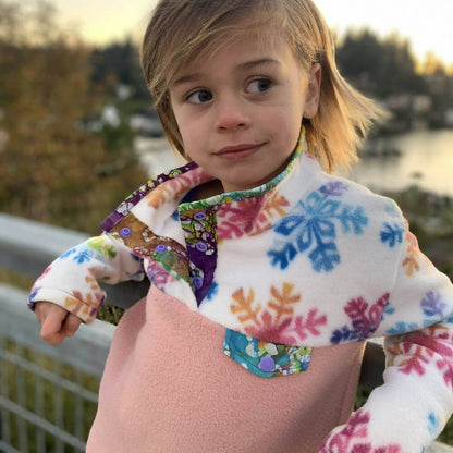 Enfant portant le Mini-SHERPA - Polaire mixte pour enfants du 2 au 16 Ans, patron de couture pdf à télécharger, avec motifs colorés.