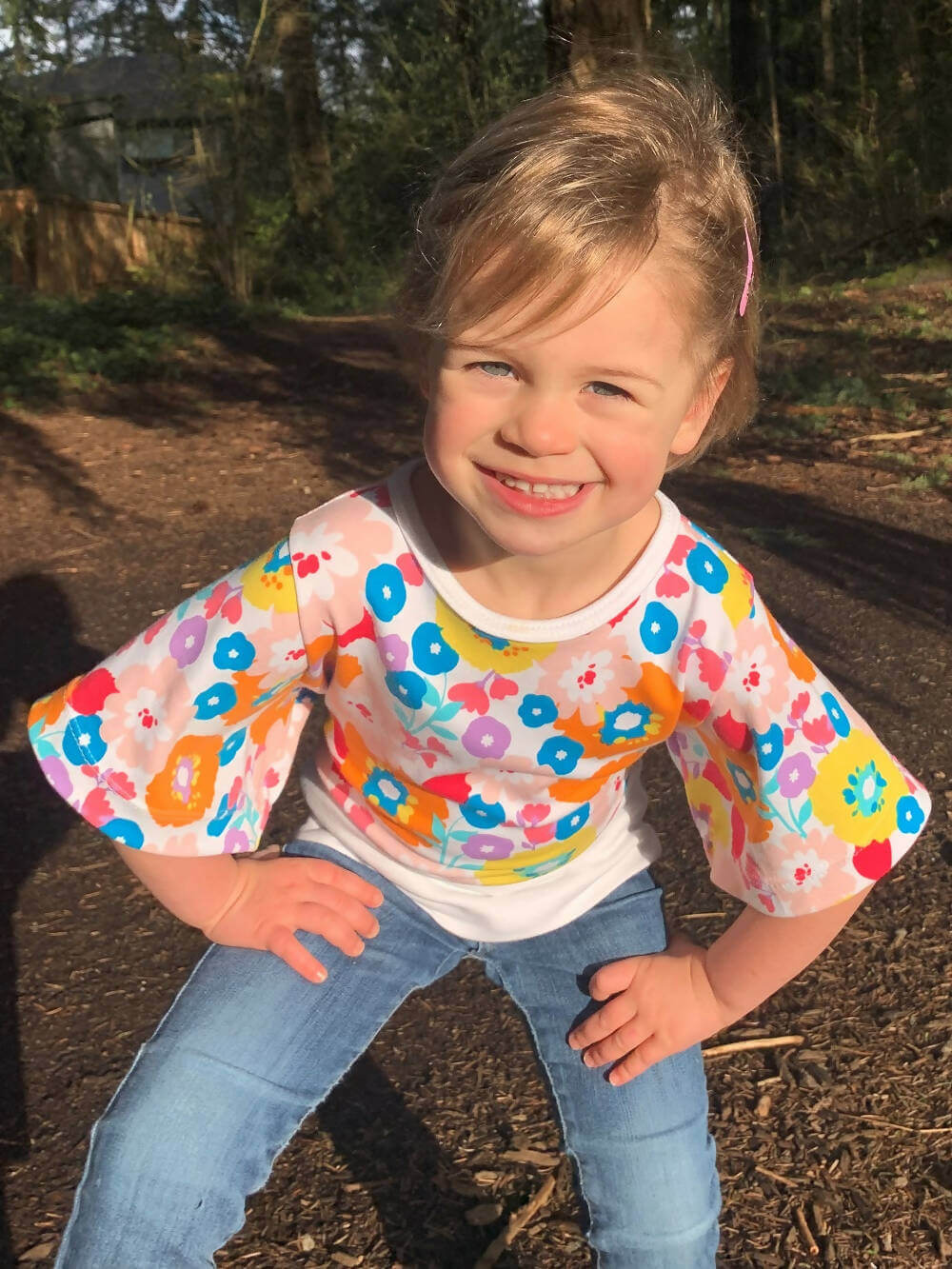 Enfant portant le Mini-VANOU - Top pour filles du 2 au 16 Ans, patron de couture pdf à télécharger, avec motif floral coloré.