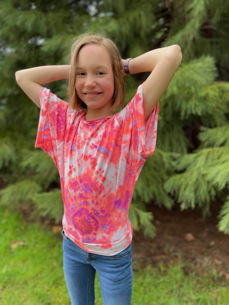 Fille portant le top Mini-VANOU - Top pour filles du 2 au 16 Ans, avec manches kimono, sur fond extérieur. Patron de couture PDF à télécharger.